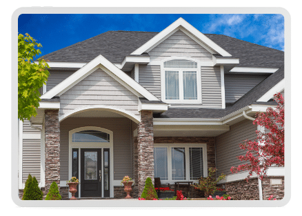 A stunning custom home with a dramatic roof, ornate details, and a welcoming front porch and yard.